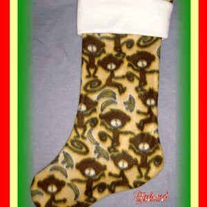 May include: A brown and tan Christmas stocking with a white cuff. The stocking is decorated with a pattern of brown monkeys and bananas.
