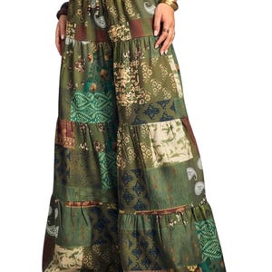 May include: Olive green patchwork palazzo trousers with a drawstring waist. The wide-leg trousers feature floral and paisley patterns in green, brown, and cream. The trousers have a tiered design.