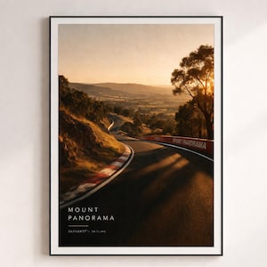 May include: A framed print featuring a scenic view of Mount Panorama racetrack at sunset. The image showcases the winding track with red and white curbing, surrounded by lush greenery and rolling hills. Text on the print reads "Mount Panorama, Bathurst Skyline."