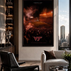 May include: A framed poster featuring a stadium scene with the Virginia Tech logo, VT, in maroon and orange. The image shows a crowded stadium with fans and the text "Virginia Tech" at the top. The poster is displayed in a modern living room setting.