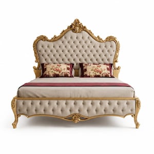May include: A bed frame featuring a gold-finished wooden structure with ornate carvings. The headboard and footboard are upholstered in beige fabric with button tufting. Two rectangular pillows with floral patterns and a dark red runner are included.