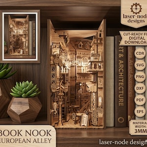 May include: A wooden book nook featuring a detailed European alley scene with buildings, street lamps, and tables. The design is laser-cut and includes the text "BOOK NOOK EUROPEAN ALLEY". The image also shows a framed version of the nook and books.