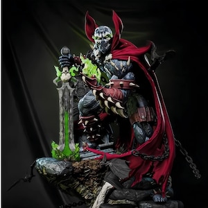 Könnte beinhalten: Eine detaillierte Spawn-Actionfigur mit dunkelblauem und schwarzem Rüstungsanzug, einem langen, wehenden roten Umhang und Stachelhandschuhen. Die Figur hält ein großes Schwert mit leuchtend grüner Klinge auf einem felsigen Sockel mit Ketten.