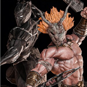 Könnte beinhalten: Ein detailliertes Sammlerfiguren-Set mit einer schwarz gepanzerten Figur mit glatter Maske und leuchtend weißen Augen, neben einer muskulösen, oberkörperfreien Figur mit gehörnter Metallmaske, orangefarbenem Haar und metallenen Armschienen.