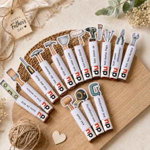 May include: A collection of decorative tools with the text "Happy Father's Day" on a tag. The tools include a hammer, screwdriver, level, and more. Each tool has a white label with German text and the word "du".