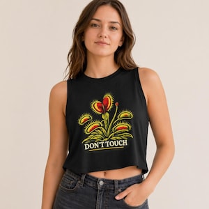 May include: Black crop top featuring a Venus flytrap plant design in red and yellow, with the words "DON'T TOUCH" in white. The sleeveless top is made of a soft fabric and is a casual style.