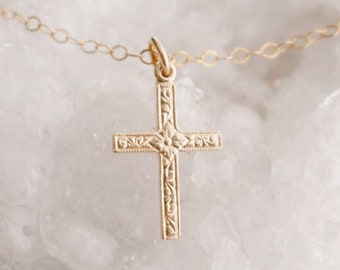 May include: A gold chain necklace with a delicate, ornate cross pendant.