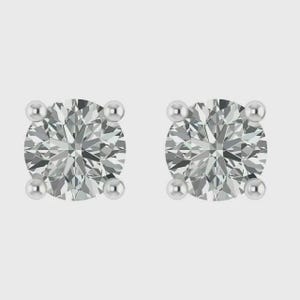May include: A pair of diamond stud earrings. Each earring features a round, brilliant-cut diamond held in place by four small, round prongs. The diamonds sparkle against a light background.