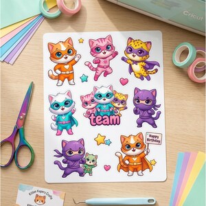 Pode incluir: Uma folha de autocolantes coloridos de gatos com fantasias de super-her&oacute;is, com a palavra "team" e um letreiro de "Happy Birthday". Os autocolantes s&atilde;o laranja, rosa, amarelo, roxo e azul. Tamb&eacute;m est&atilde;o inclu&iacute;das tesouras, fita washi e papel de artesanato.