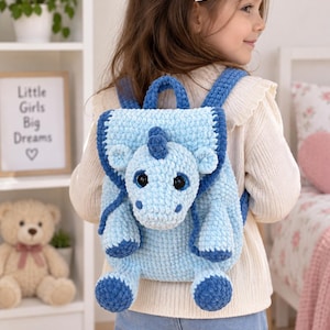 Peut inclure: Un sac à dos en crochet bleu clair représentant une licorne en peluche avec une corne, une crinière et des pieds bleu foncé. Le sac possède un rabat, deux bretelles et une poignée, le tout en fil texturé doux avec de grands yeux noirs.