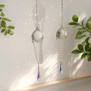 Puede incluir: Dos atrapasoles de cristal colgantes. Uno tiene una cadena plateada y el otro una cadena dorada. Cada uno presenta una bola de cristal transparente y un prisma en forma de l&aacute;grima que refracta la luz en un arco&iacute;ris de colores. Decorativo.