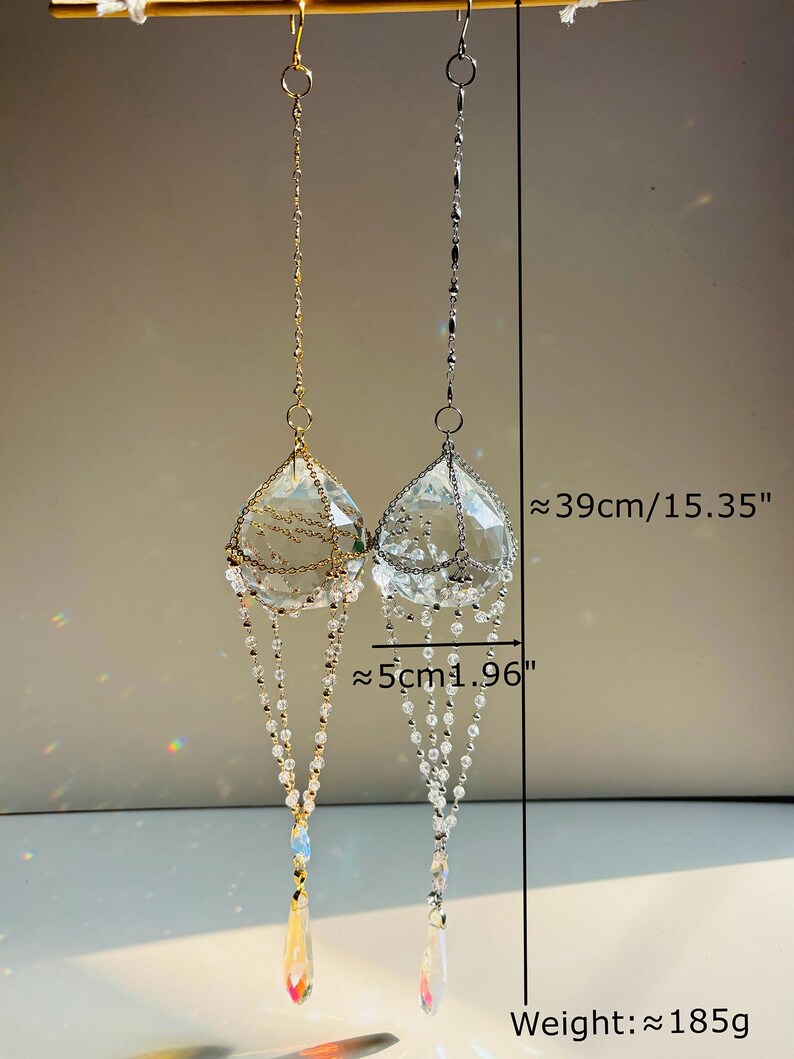 Puede incluir: Dos atrapasoles de prisma de cristal colgando de cadenas doradas y plateadas. Cada prisma mide aproximadamente 39 cm de largo y 5 cm de ancho. El peso de cada atrapasol es de aproximadamente 185 g.