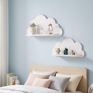 May include: Two white wall-mounted shelves shaped like clouds. The top shelf holds a small potted plant, a glass bottle, and a pink flamingo figurine. The bottom shelf holds a small white figurine, a green bottle, and a small brown deer figurine.