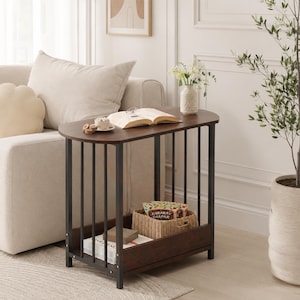 May include: A C-shaped side table with a dark brown wooden top and a black metal frame featuring vertical support bars. The table includes a lower shelf for storage, currently holding a woven basket and books, with an open design for easy access.