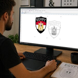 May include: A person working on a computer, designing a graphic of the Egyptian coat of arms. The design features a shield with the word "EGYPT" and the image of an eagle. The design is in color and outline form.