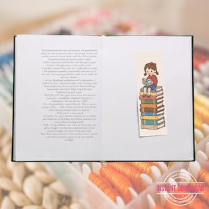 May include: An open book with printed text on the left page and a vertical bookmark on the right page. The bookmark features a pixel art illustration of a person with brown hair and a red shirt sitting on a stack of seven colourful books.