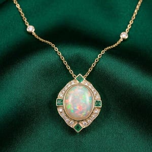 Könnte beinhalten: Eine goldene Halskette mit einem ovalen Anhänger mit einem großen Opalstein. Der Anhänger ist von kleinen Diamanten und smaragdgrünen quadratischen Steinen umgeben. Die Halskette hat kleine Diamantakzente. Der Hintergrund ist ein dunkelgrüner Stoff.