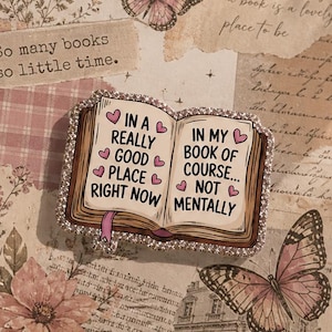Op de afbeelding: Transparante tablethoes met een collage-ontwerp. Het heeft vlinders, bloemelementen en tekst. De hoes heeft een met strass versierd boekvormig ornament met de tekst "In a really good place right now" en "In my book of course... not mentally."