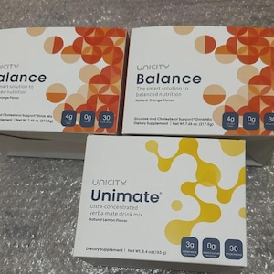 May include: Three white boxes of Unicity dietary supplements. Two boxes are labeled "Balance" with orange graphics and "Natural Orange Flavor." The third box is labeled "Unimate" with yellow graphics and "Natural Lemon Flavor."