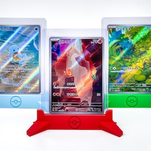 May include: Three Pokémon card displays in blue, red, and green. Each display holds a card with Japanese text and colorful illustrations. The displays have a Pokémon logo and are designed to stand upright.