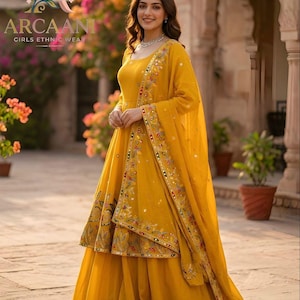 Puede incluir: Una mujer con un atuendo &eacute;tnico amarillo brillante. El conjunto incluye una falda larga y fluida, una blusa con bordados intrincados y una bufanda a juego. El atuendo est&aacute; adornado con bordados y adornos coloridos. El texto "ARCAANI GIRLS ETHNIC WEAR" es visible.