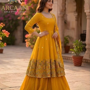 Puede incluir: Un vestido &eacute;tnico amarillo vibrante con un dobladillo bordado floral. El vestido presenta una parte superior de manga larga y una falda en capas. La marca "ARCAANI GIRLS ETHNIC WEAR" es visible.