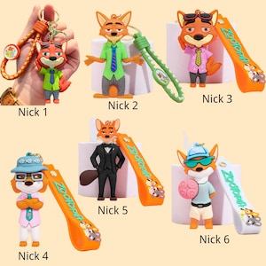 May include: A collection of six Nick Wilde keychains from the movie Zootopia. Each keychain features a different outfit and pose for the fox character. The keychains have orange straps with the word "Zootopia" printed on them.