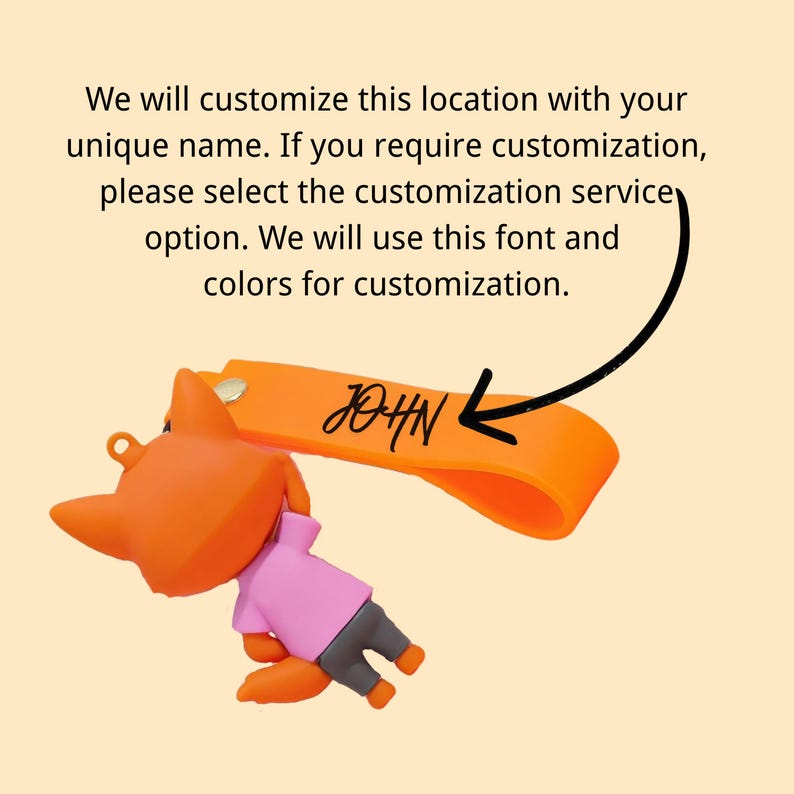 May include: Orange fox keychain with a pink shirt and gray pants. The keychain has an orange strap with the name "JOHN" in black script. The text above the keychain says, "We will customize this location with your unique name."