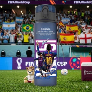 May include: A blue water bottle featuring a soccer player graphic with the text "MESSI 10" and "LIONEL MESSI". The bottle has a black cap and a strap. The text "CASNO" and "HEALTHY SAFELY GREEN OUTSTANDING.COME FROM THE WATER LIFE STYLE" is also visible.