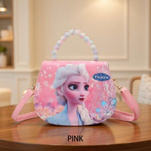 May include: Pink purse featuring a graphic of Elsa from Frozen. The purse has a beaded handle and a detachable pink shoulder strap. The word "PINK" is printed at the bottom of the purse.