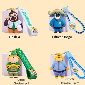 May include: Four Zootopia character keychains. Flash 4 is a sloth with a white shirt, green tie, and orange pants. Officer Bogo is a blue buffalo. Officer Clawhauser 1 is a tiger. Officer Clawhauser 2 is a yellow cat.