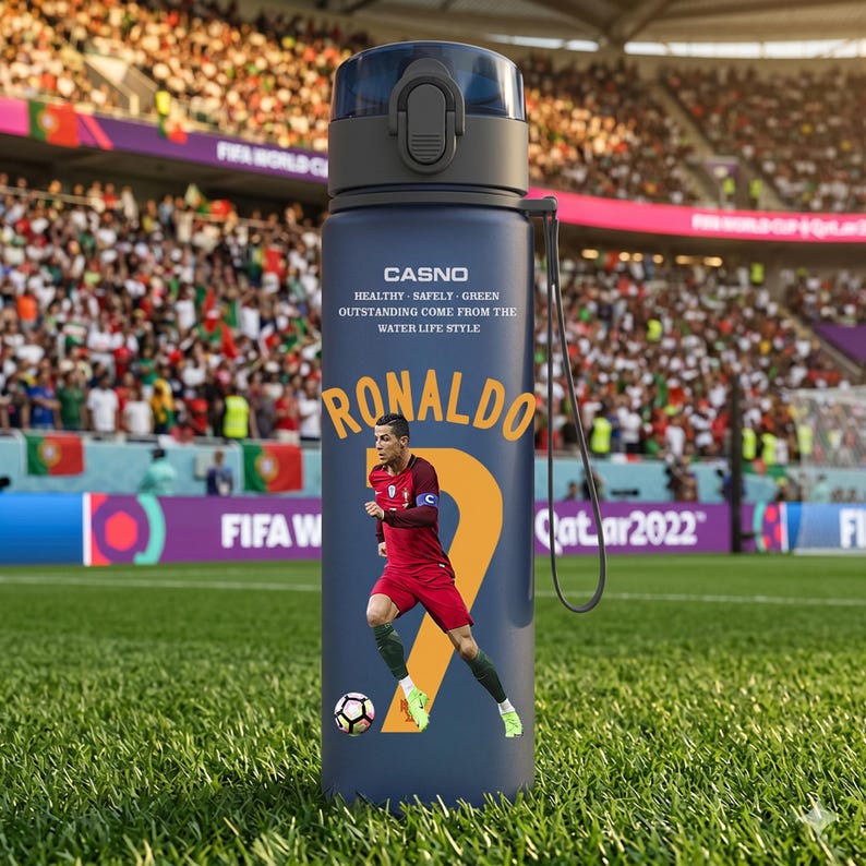 May include: A navy blue water bottle featuring a soccer player graphic and the name "Ronaldo." The bottle has a black cap and a strap. Text on the bottle reads "CASNO" and "HEALTHY - SAFELY - GREEN OUTSTANDING COME FROM THE WATER LIFE STYLE."