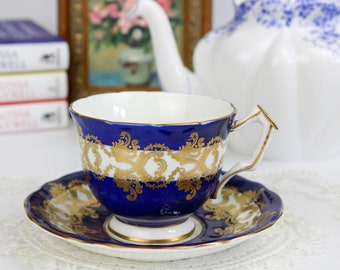 May include: A blue and gold teacup and saucer set with a delicate floral pattern. The cup and saucer are made of fine china and have a gold trim.
