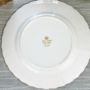 May include: White ceramic plate with a gold rim and a gold inscription on the bottom that reads "Royal Albert Bone China England 1st  Qual."