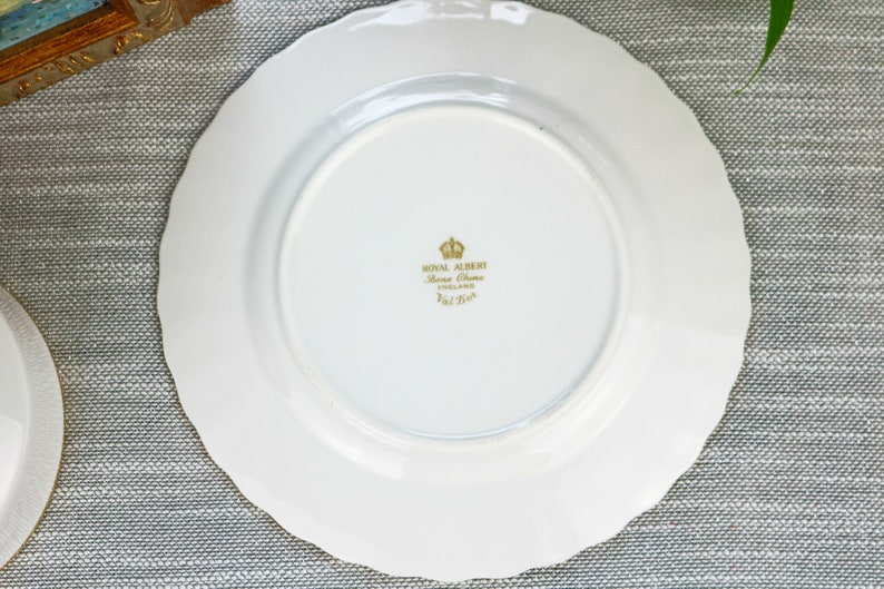 May include: White ceramic plate with a gold rim and a gold inscription on the bottom that reads "Royal Albert Bone China England 1st  Qual."