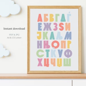 May include: A framed print featuring a colorful alphabet in various pastel shades. The letters are arranged in a grid, with each row displaying a different set of characters. The text "Instant download" is visible, along with "PDF & JPG" and "A4 & US Letter".