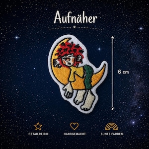 Op de afbeelding: Een geborduurde patch met een stripfiguur met rood haar op een gele halve maan. De figuur draagt een geel shirt en een groene broek. Een verticale lijn geeft een hoogte van 6 cm aan. De tekst Aufnäher, DETAILREICH, HANDGEMACHT en BUNTE FARBEN is zichtbaar.