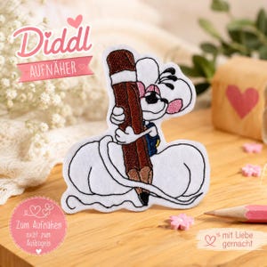 Könnte beinhalten: Ein weißer Stickaufnäher, der eine Cartoon-Mausfigur zeigt, die einen großen braunen Stift hält. Die Maus hat rosa Ohren und trägt blaue Kleidung. Der Aufnäher hat einen weißen Rand und ist zum Aufnähen auf Textilien vorgesehen.