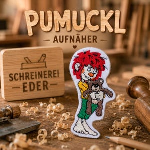Puede incluir: Un parche bordado que muestra al personaje Pumuckl con cabello rojo brillante, camisa amarilla y pantalones verdes, sosteniendo un pequeño oso de peluche marrón. El parche tiene fondo blanco y se encuentra sobre un fondo de madera con texto.