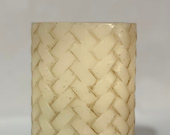 May include: A white pillar candle with a woven pattern.