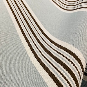 May include: Close-up of a blue and brown striped fabric. The fabric has a woven texture and is made of cotton.