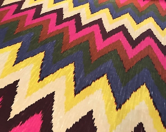 May include: A colorful fabric with a chevron pattern in shades of pink, yellow, blue, brown, and white.