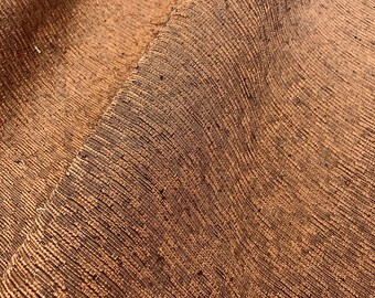 May include: Close-up of a brown woven fabric with a textured surface. The fabric has a subtle sheen and a slightly irregular weave.
