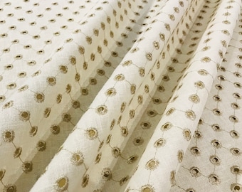 May include: White fabric with a subtle pattern of small, gold circles. The fabric is folded in a way that shows the pattern repeating.