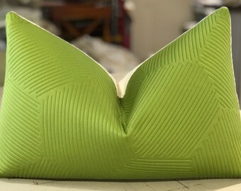 May include: A green pillow with a geometric pattern. The pillow is made of a soft, textured fabric and has a white border.
