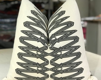 May include: A white pillow with a black geometric pattern. The pattern is made up of overlapping lines that create a symmetrical design.