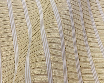 May include: Beige fabric with a textured pattern of white stripes and raised rectangles. The fabric has a subtle wave pattern.