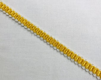 May include: White and yellow braided trim with a wavy pattern.