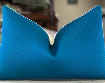 May include: A blue and white decorative pillow with a geometric pattern. The pillow is made of a soft, textured fabric.