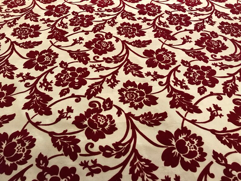 K&ouml;nnte beinhalten: Roter Blumendruck auf cremefarbenem Hintergrundstoff. Der Stoff hat ein erhabenes, strukturiertes Design.